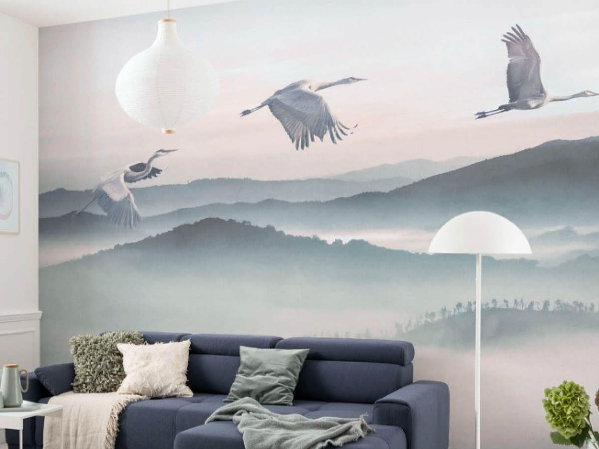 Ein in Blau gehaltenes Wohnzimmer mit großer Tapete mit Störchen
