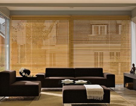 Eine hellbraune große Holzjalouse in einem Wohnzimmer.