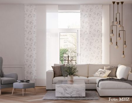 Ei weißer Flächenvorhang mit dezenten Motiven im Wohnzimmer.