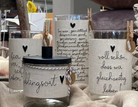 Handgefertigte Teelichter aus Glas mit Stoff ummantelt und Sinnsprüchen wie "Lieblingsort"